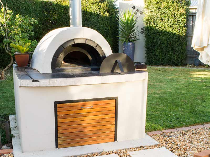Wood fired pizza oven with timber door and tiled bench top