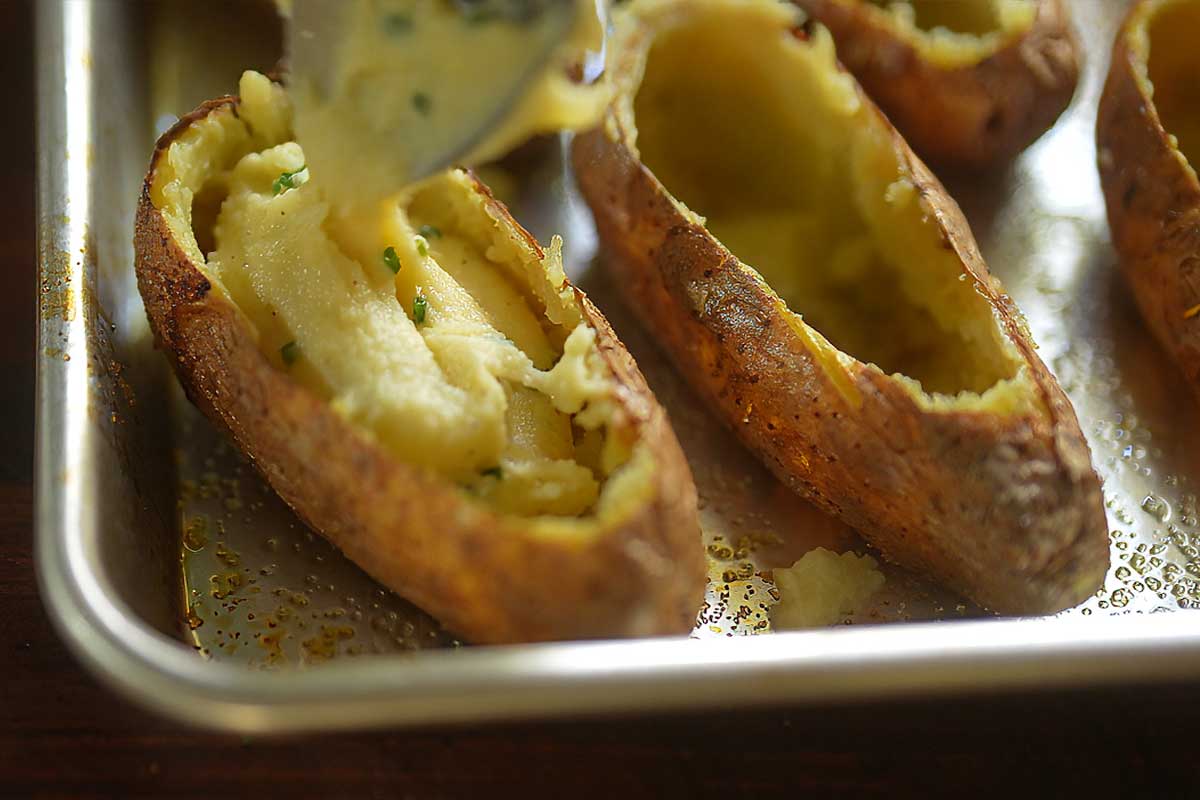 Spooning mixture into potatoes