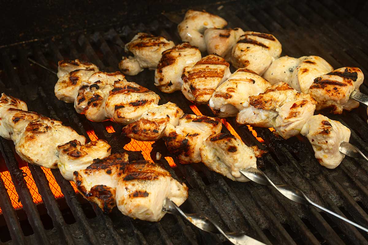 Chicken skewers grilling on barbecue with light char marks
