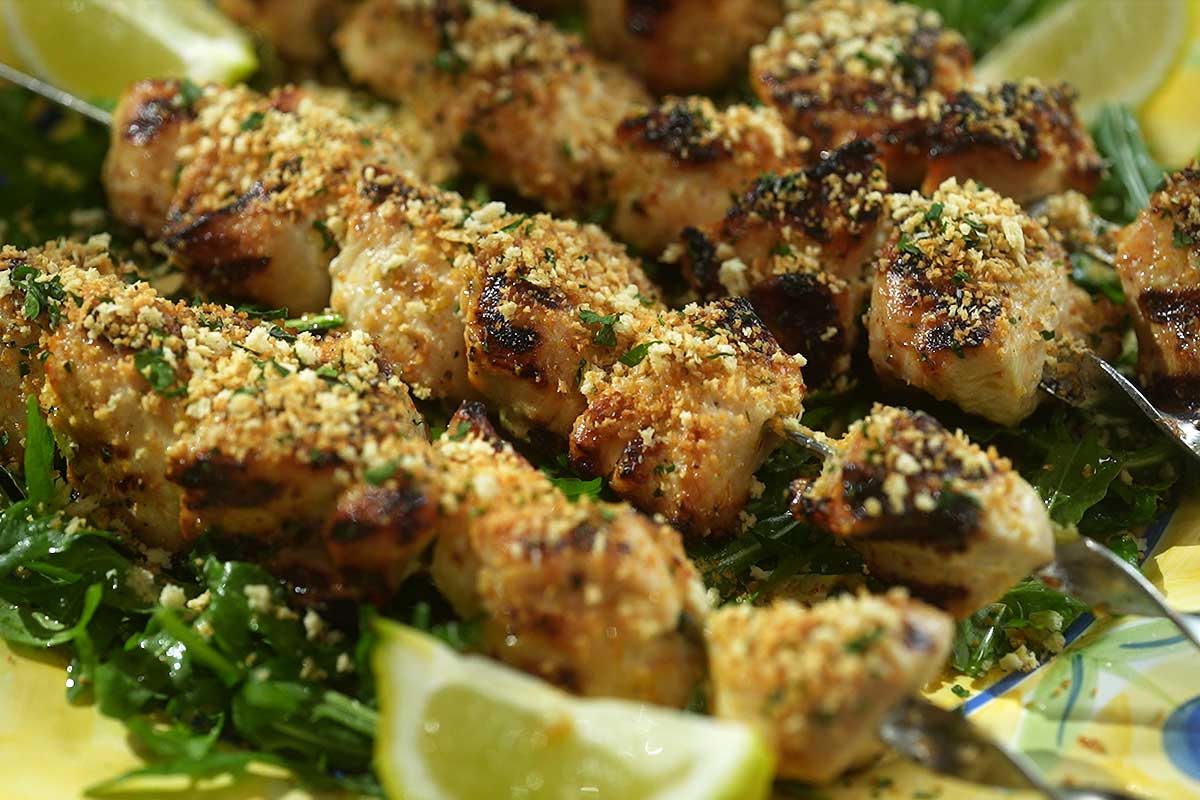 Chicken Spiedini plated with arugula and lemon wedges