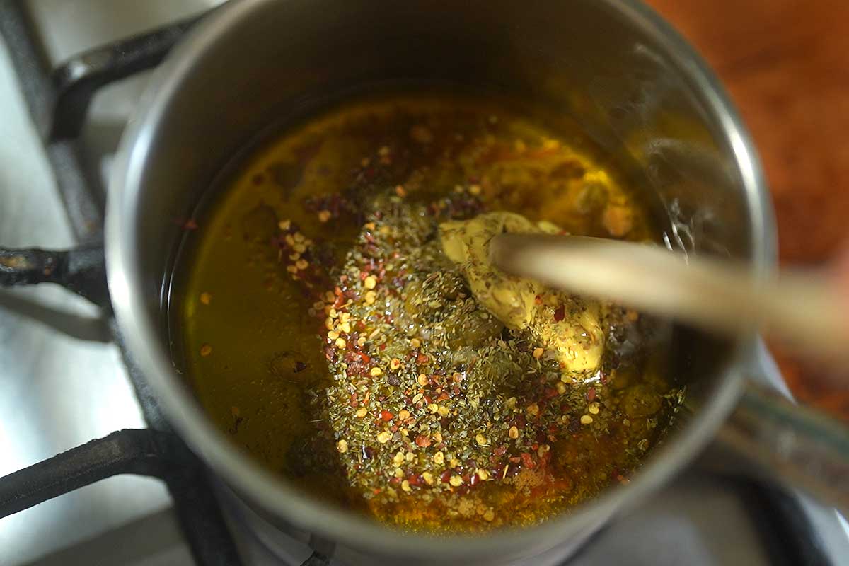 Anchovies melting into warm olive oil with garlic in small pan