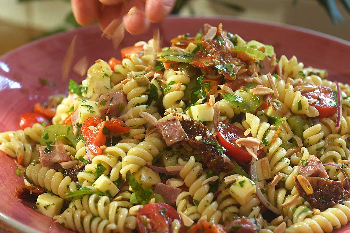 Smoky Italian Pasta Salad finished with basil pine nuts and olive oil drizzle