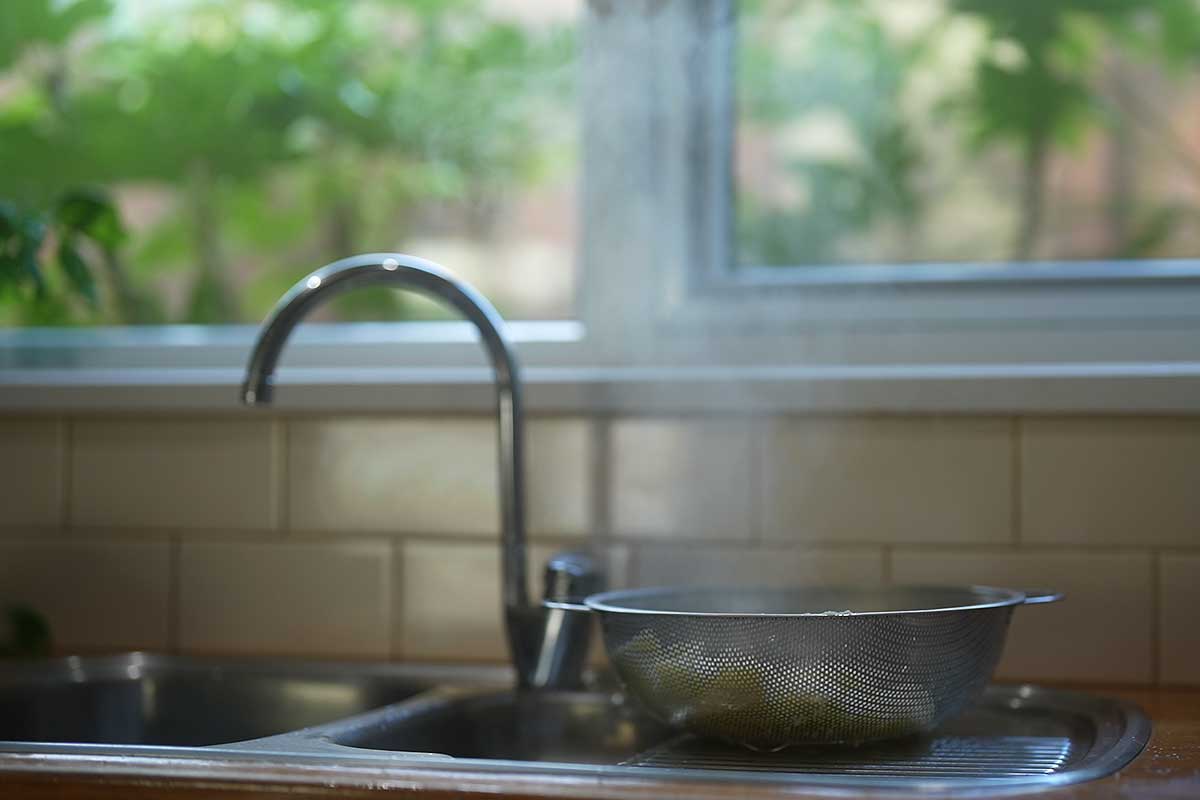 Close-up of boiled potato cubes steaming dry in a colander
