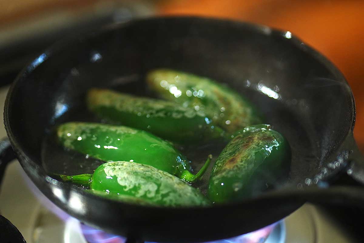 Jalapeño peppers blistering in the frying pan with flaky sea salt