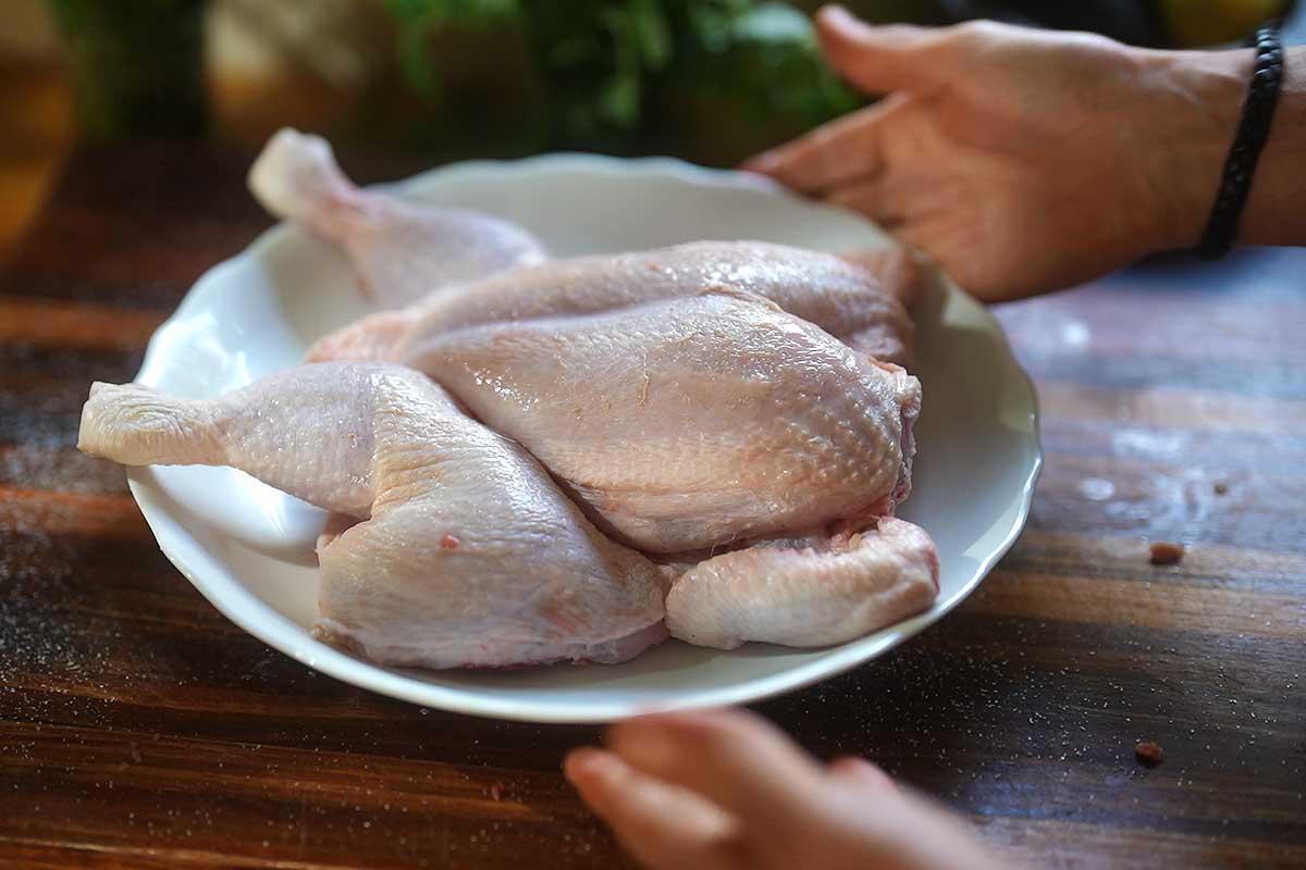 Salted chicken sitting uncovered on a tray in the fridge, skin visibly dry