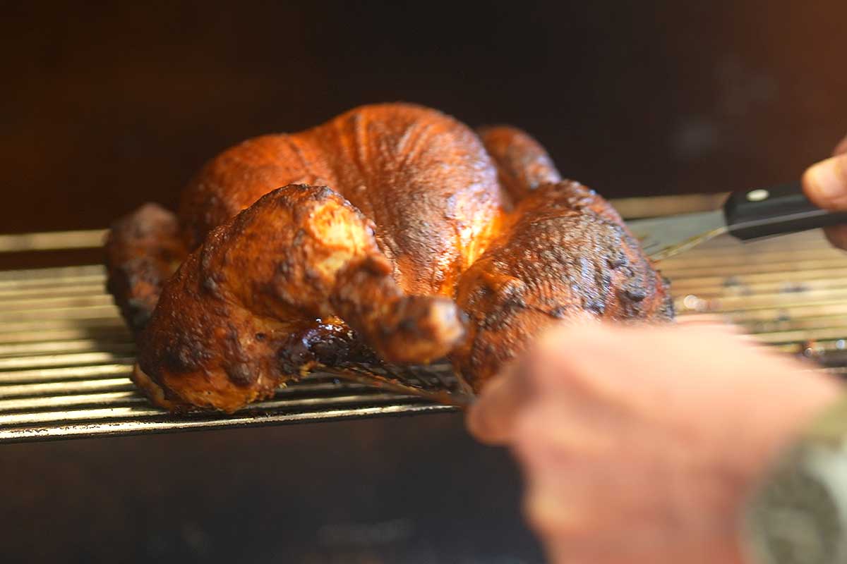Chicken over direct flame getting initial colour, flames visible