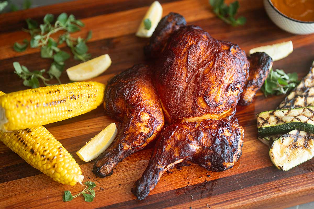Overhead of the full plate, chicken, fries, grilled vegetables and lemon wedges]