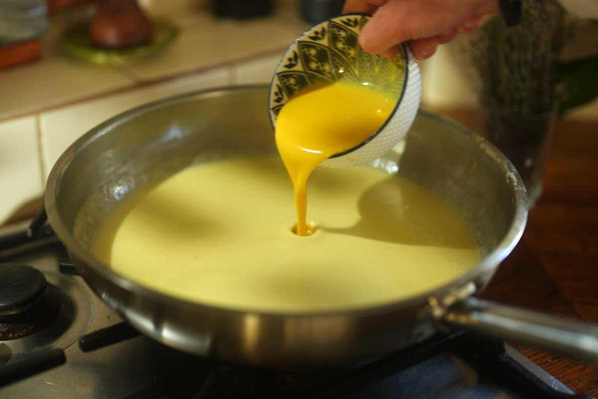 Whisking egg yolks and cream into the sauce off the heat]