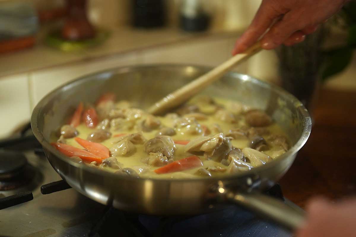 the finished creamy sauce over the chicken and vegetables in the pot]