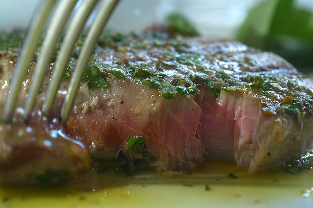 Tuna steak on a chopping plate showing the pink centre against the charred crust