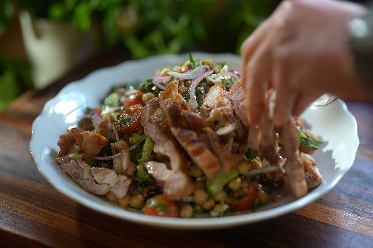 Sliced golden chicken arranged over dressed pulse salad 