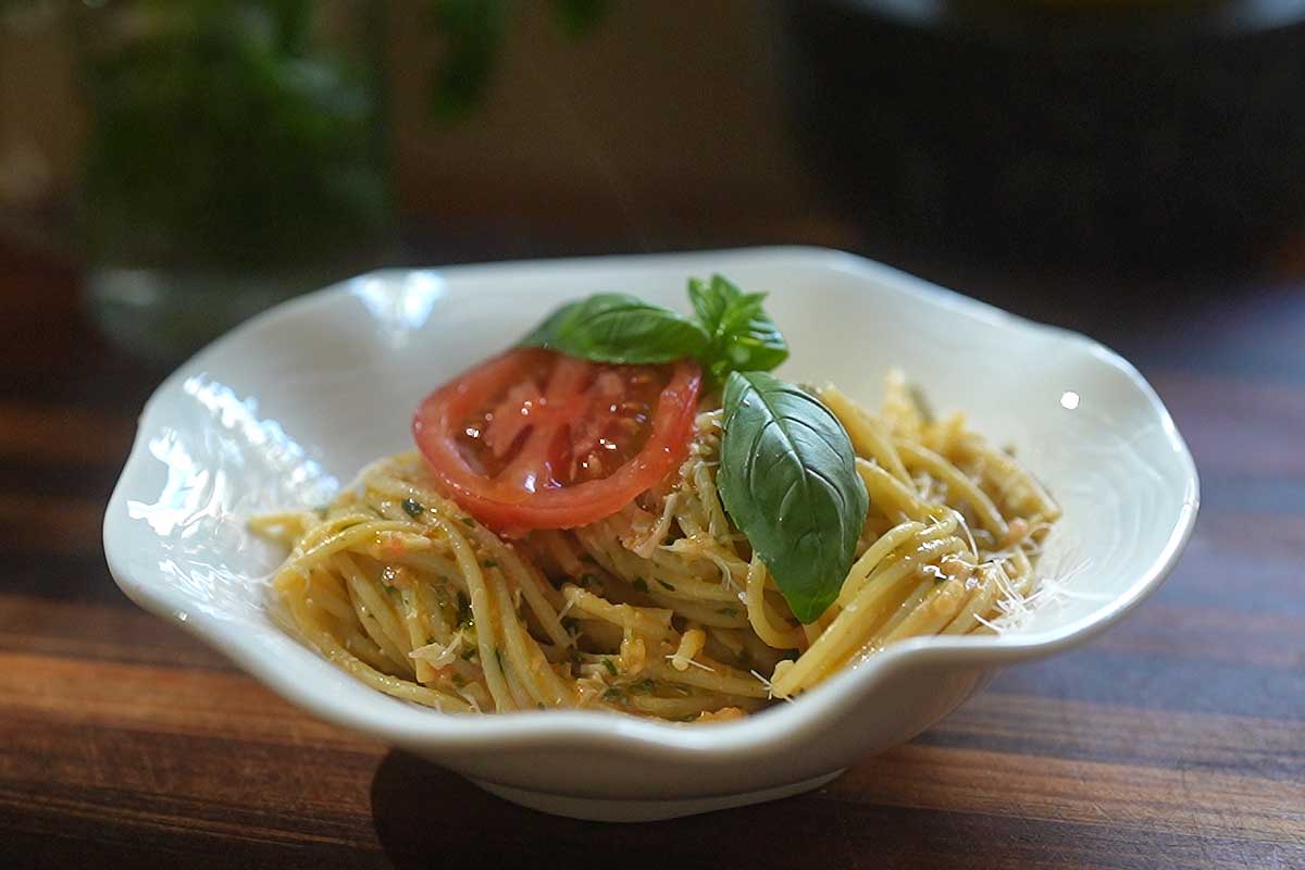 Close up of the finished dish plated, garnished with extra Pecorino, basil leaves and a slice of warm peeled tomato]