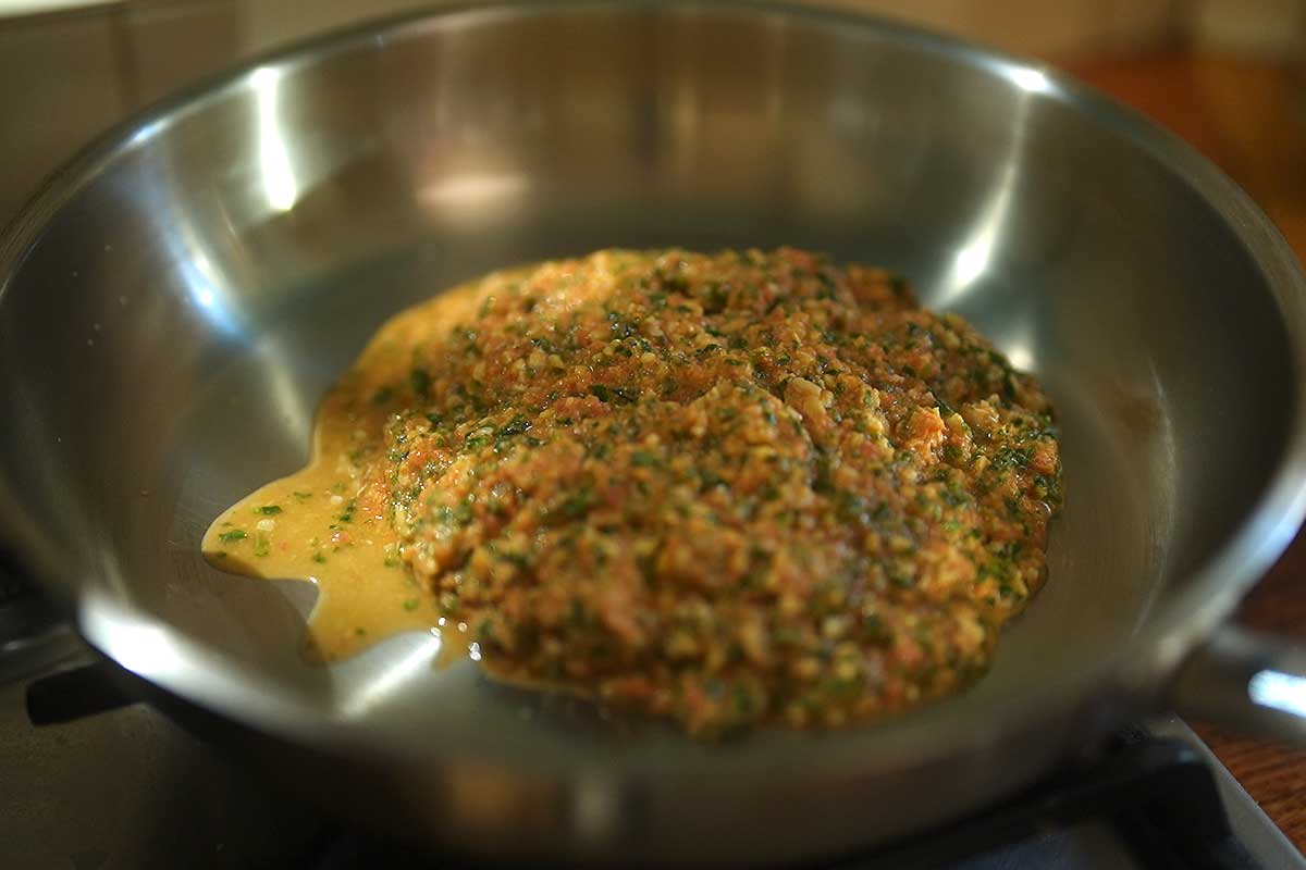 Detail shot of the raw sauce being spooned into the warm pan