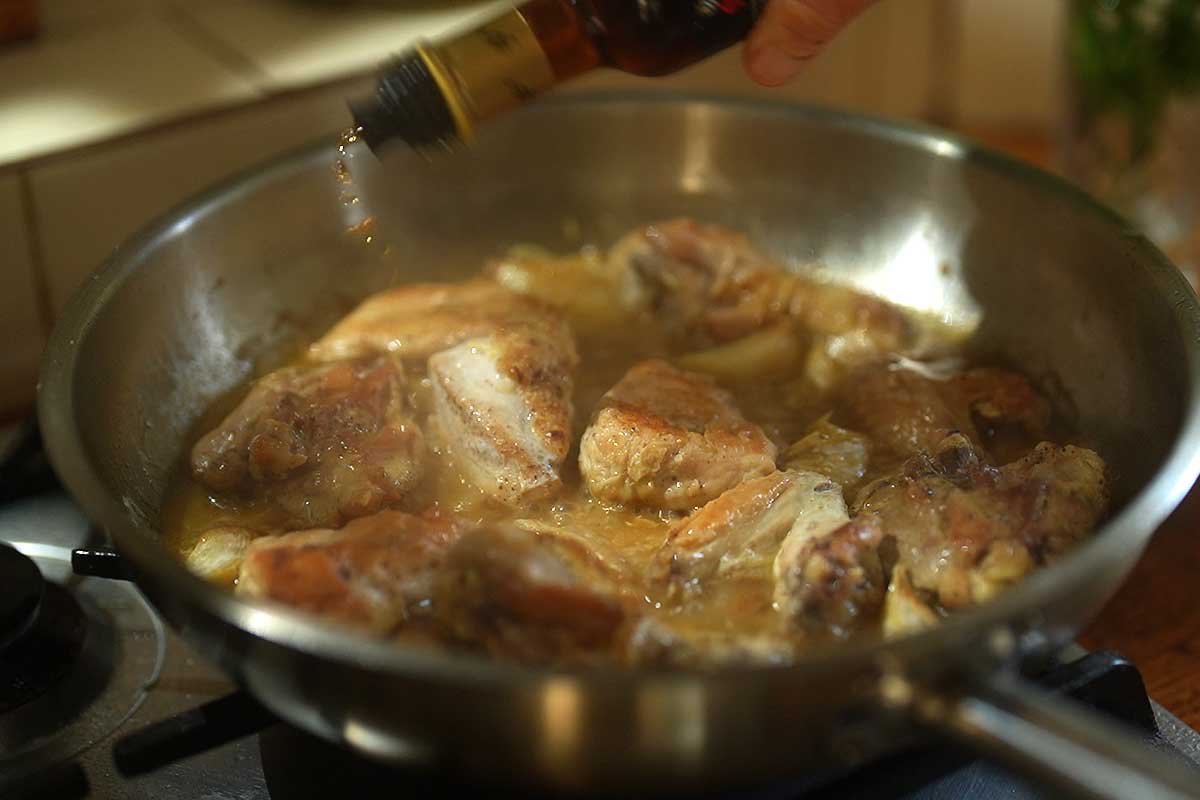 Sherry vinegar being poured into the pan with steam rising off the sauce]