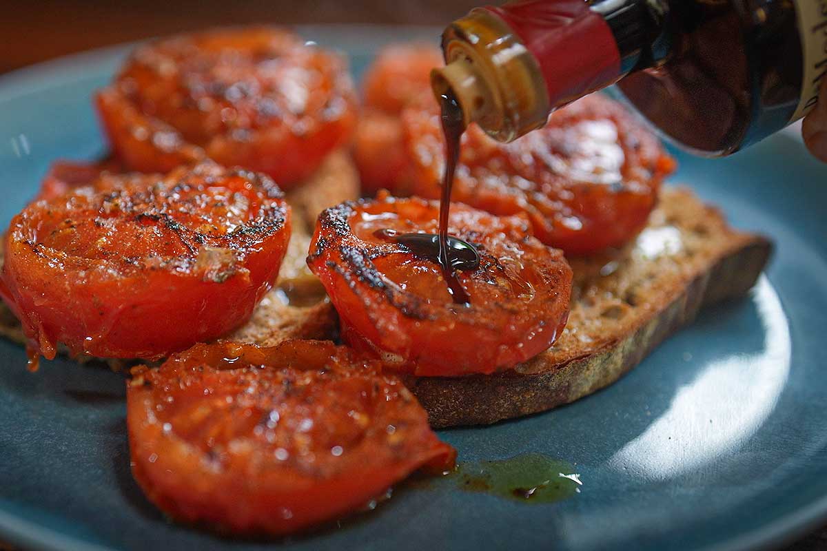 Close up of the balsamic vinegar being drizzled over the finished dish