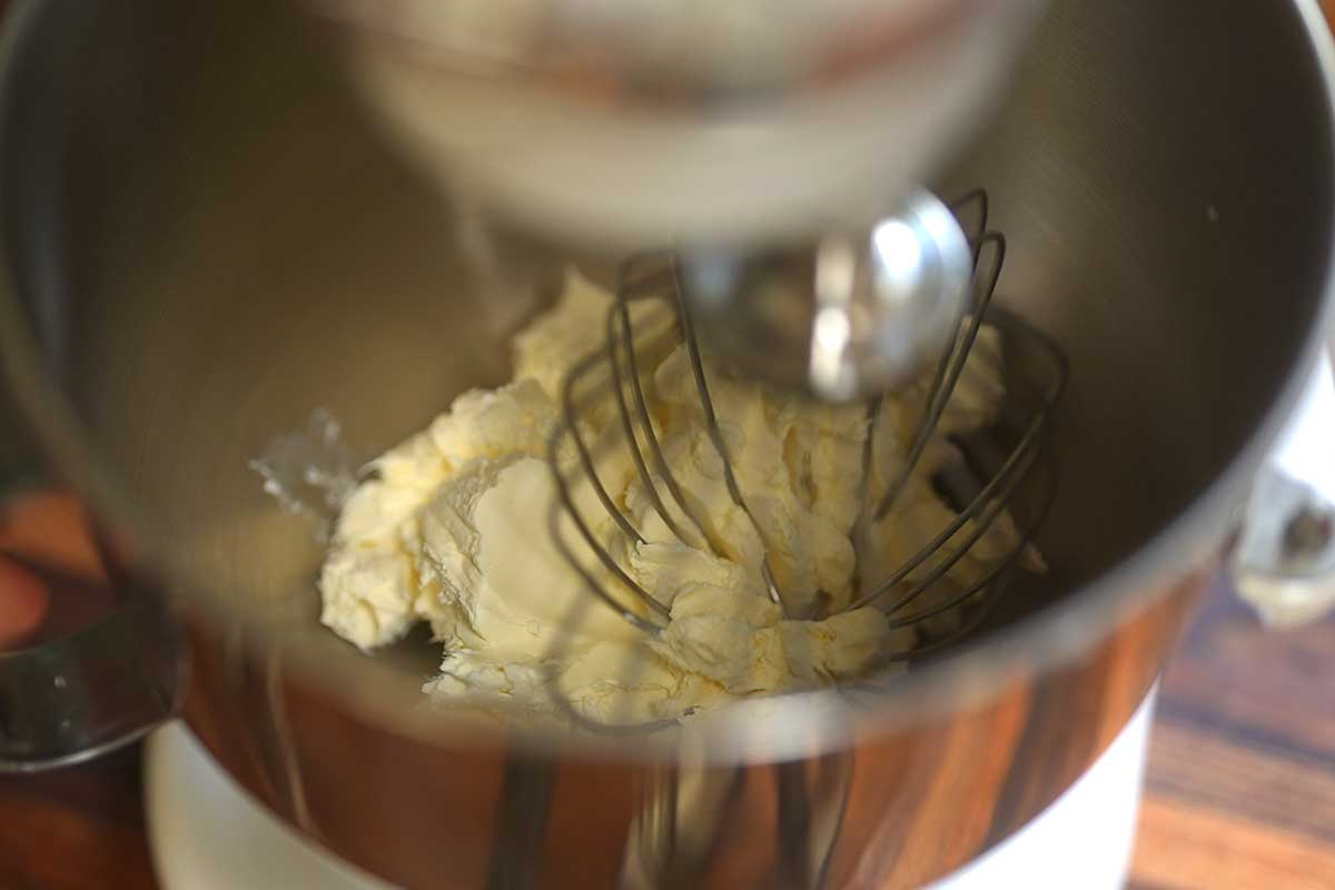 Cream cheese being whisked smooth in a large mixing bowl