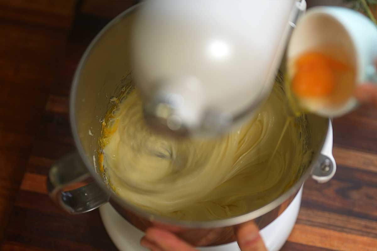 Eggs being whisked into the cream cheese mixture one at a time