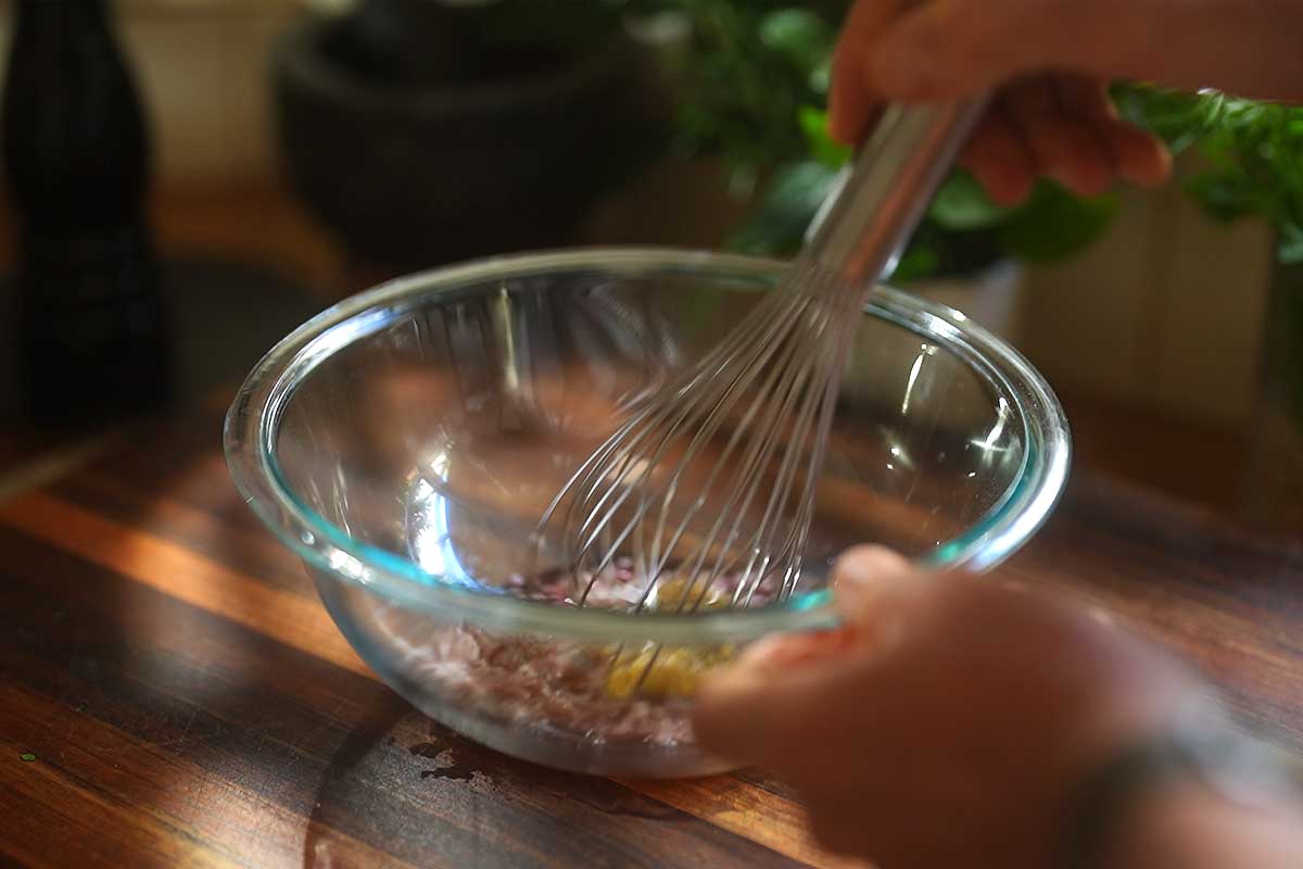 Whisking olive oil into the shallot, red wine vinegar, Dijon and honey