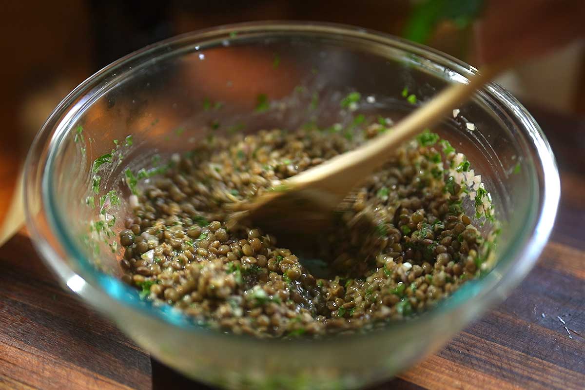 Tossing the warm lentils with the Dijon vinaigrette and parsley