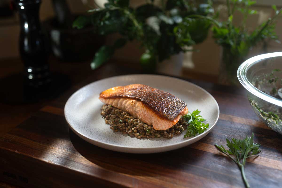 The finished plate, salmon skin side up on the warm lentils