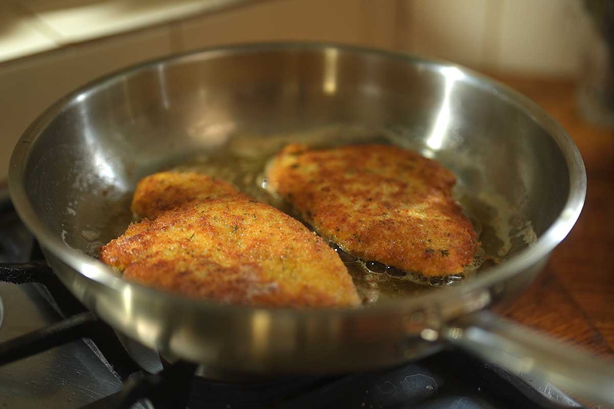 Schnitzels frying in the pan, golden and crisp, butter foaming