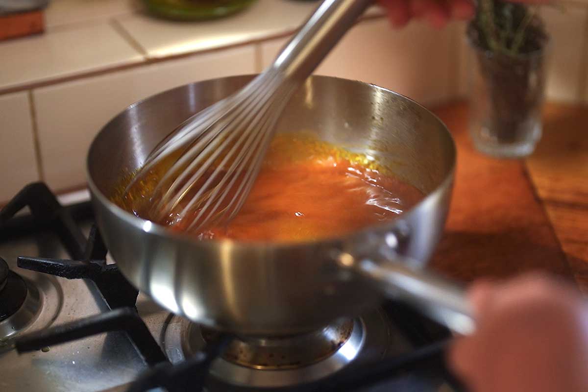 Brava sauce being whisked in the frying pan as it thickens