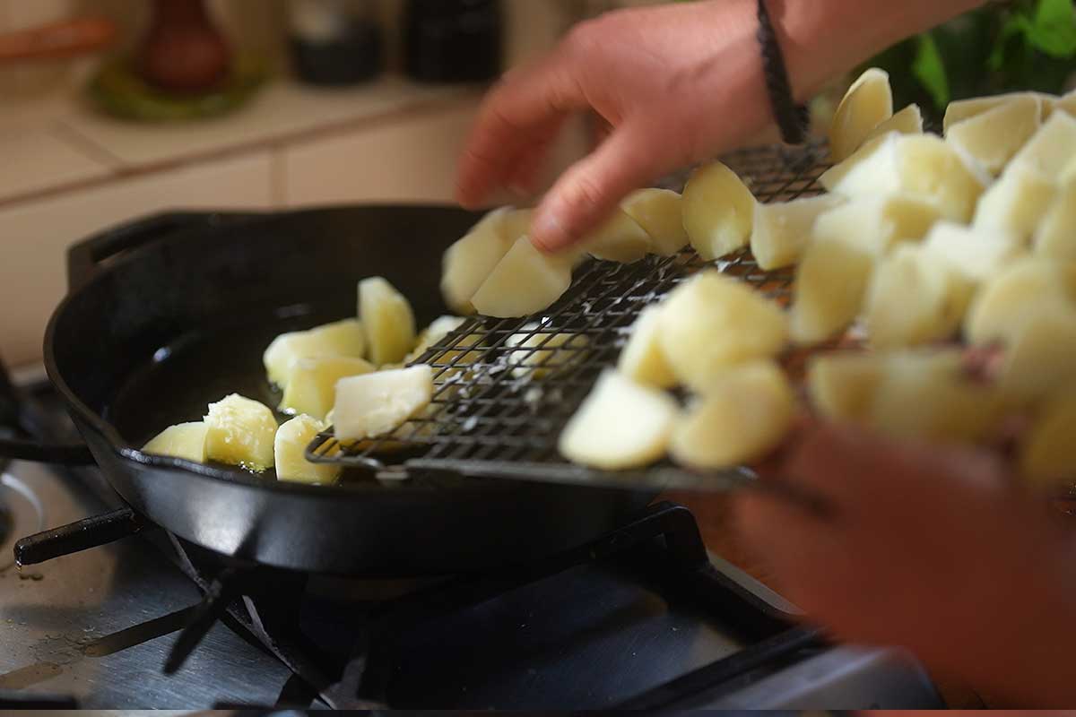 Potatoes being lowered into hot oil for the first fry