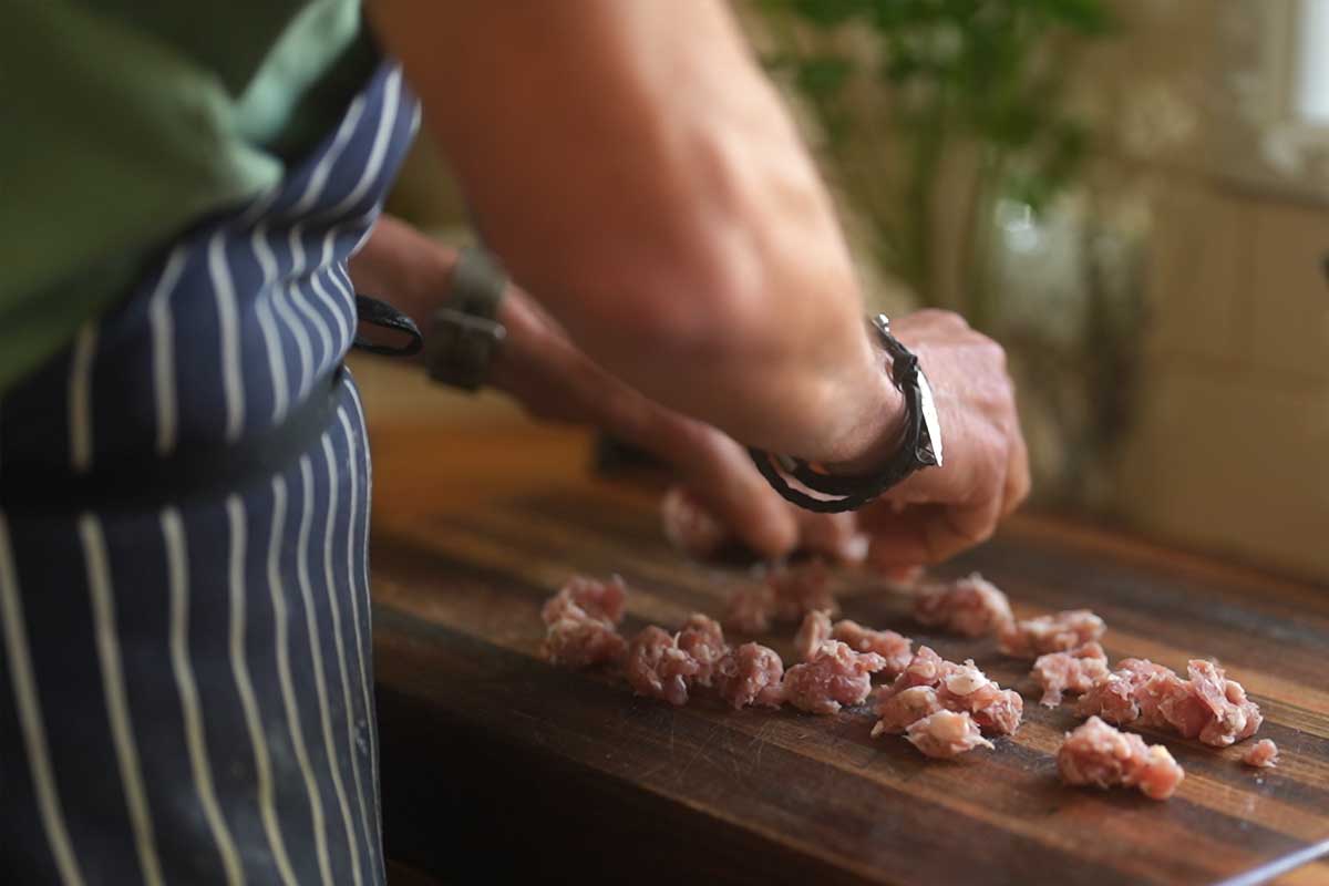 Sausage meat being squeezed out of the casings and broken into rough chunks