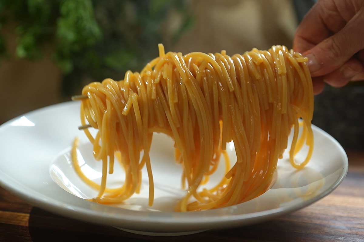 Pasta al Brodo di Pomodoro twirled in bowl with fresh basil and olive oil]