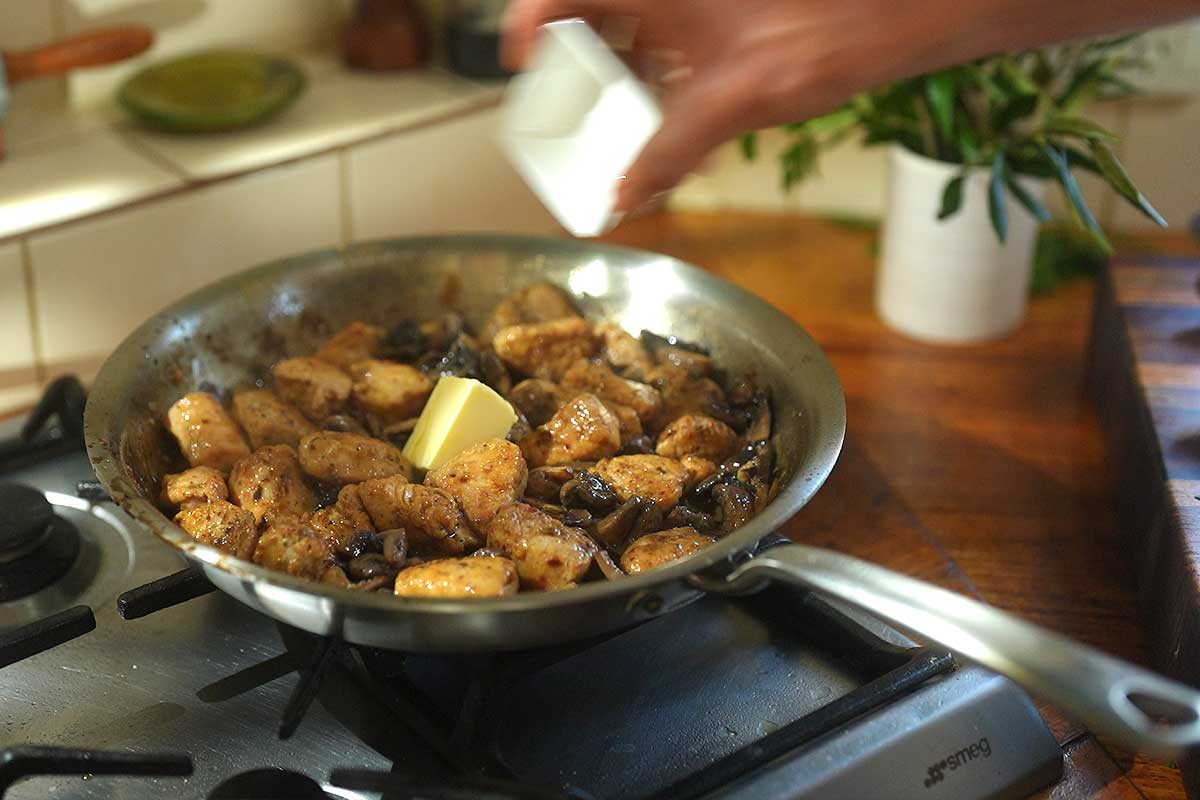 Cold butter being stirred into sauce off the heat creating glossy finish