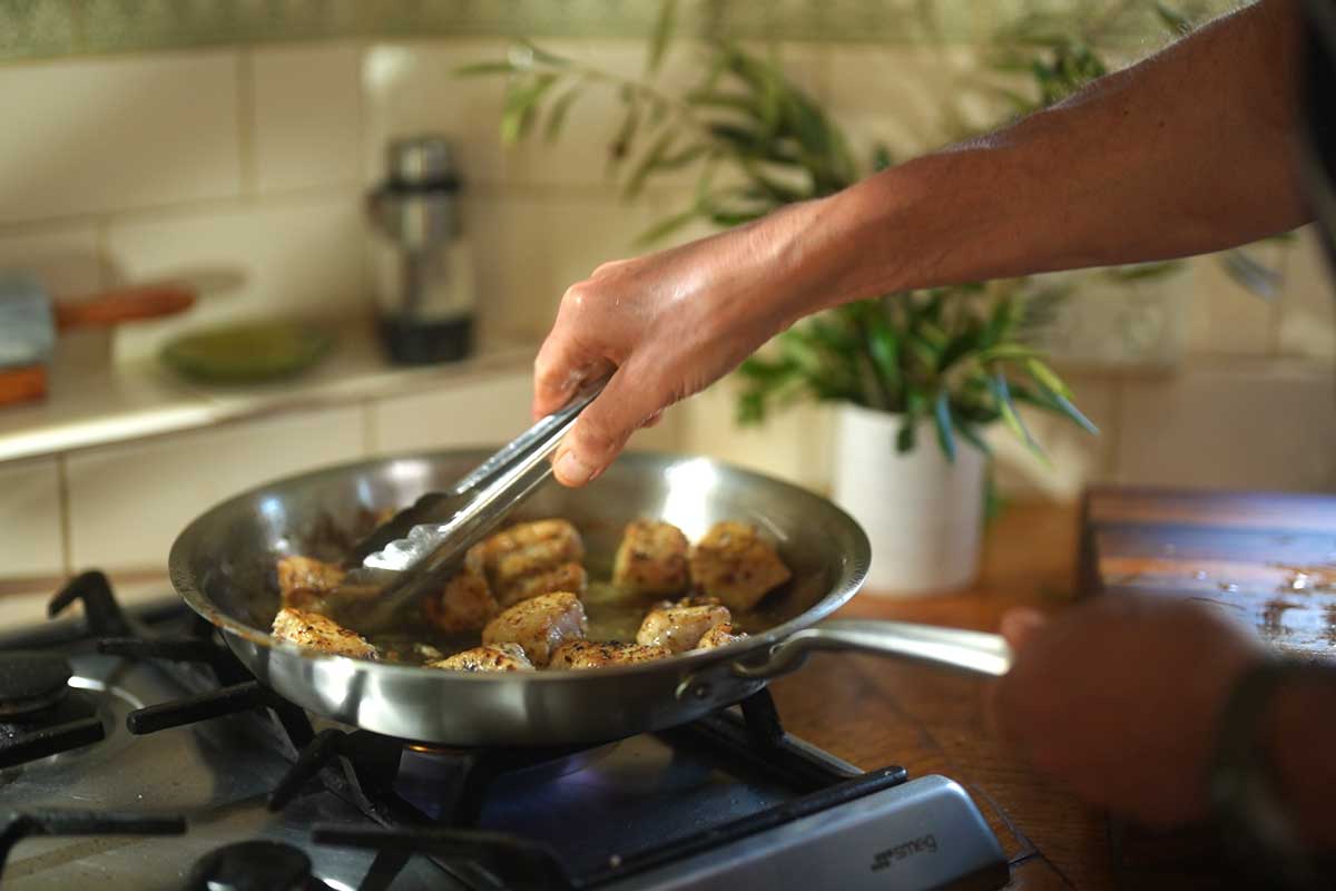 Chicken pieces browning golden in single layer in same pan as mushrooms