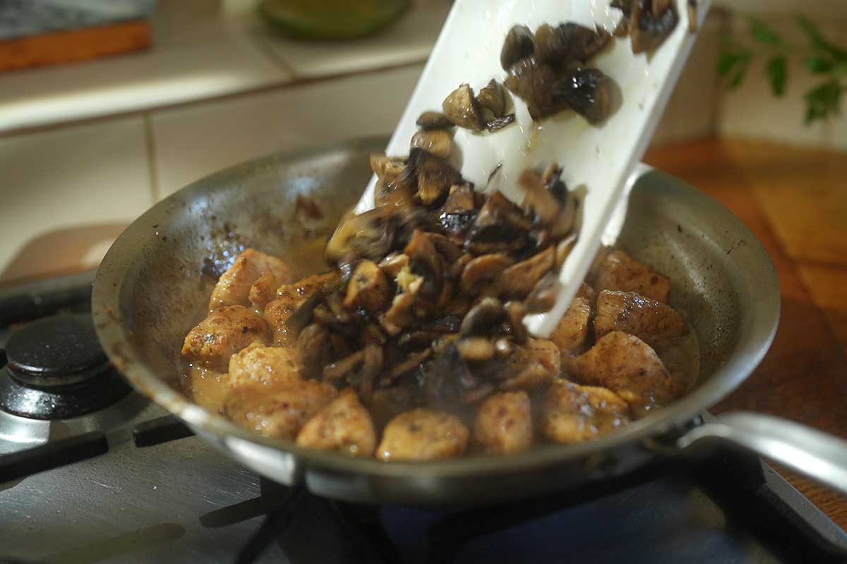 Mushrooms returned to pan with chicken simmering in white wine sauce